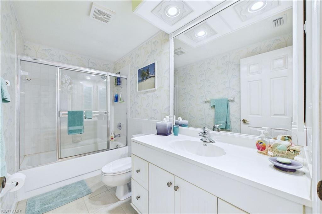 Bathroom featuring vanity, combined bath / shower with glass door, light tile patterned flooring, wallpapered walls, and recessed lighting