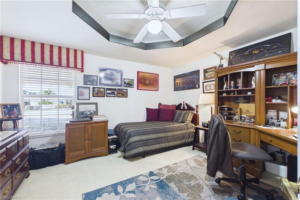 Bedroom with a desk, light colored carpet, a textured ceiling, and a ceiling fan