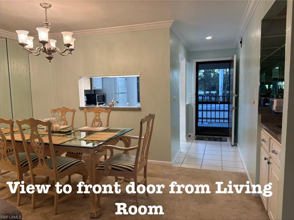 Dining room featuring ornamental molding, light colored carpet, suspended lighting, and light tile patterned floors
