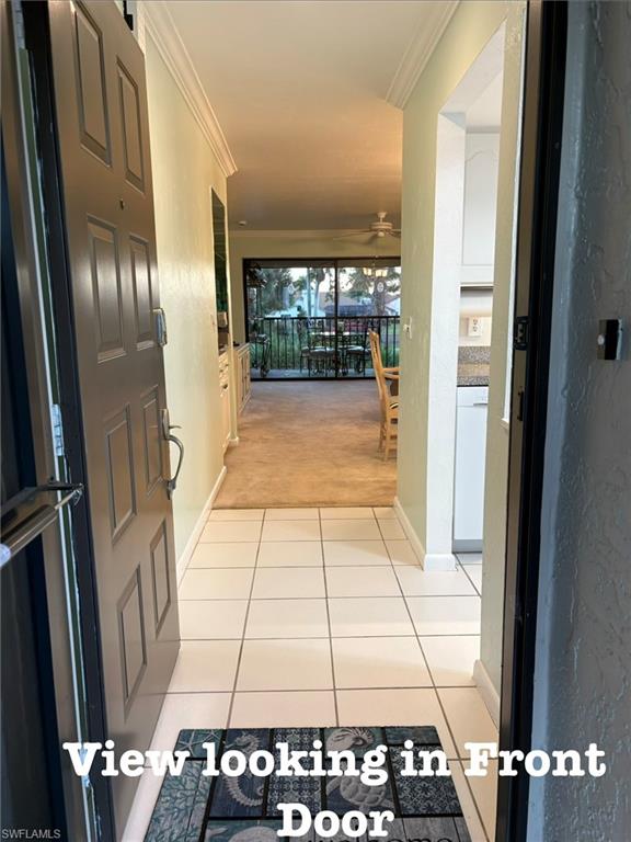 Hall featuring light carpet, crown molding, and light tile patterned flooring