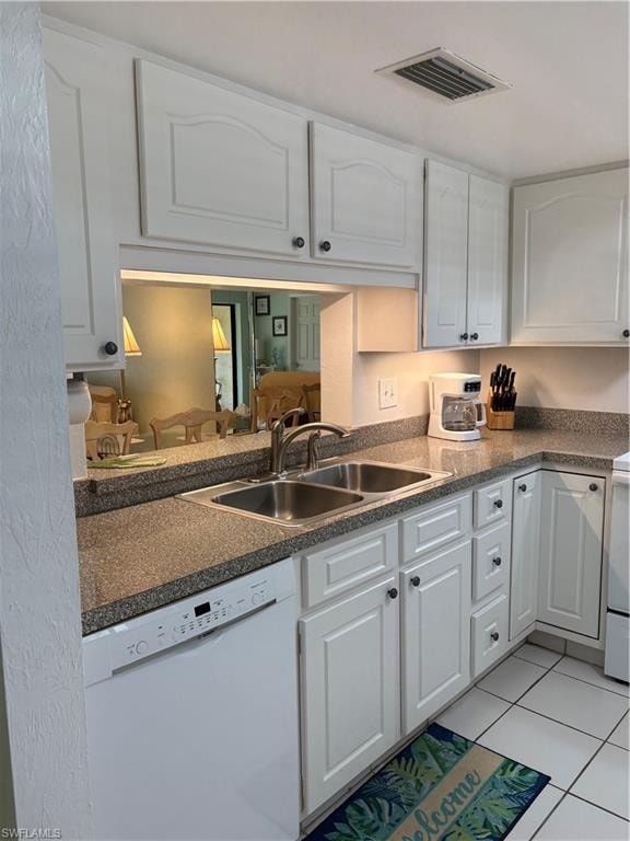 Kitchen featuring white cabinets, dishwasher, light tile patterned floors, range, and dark countertops