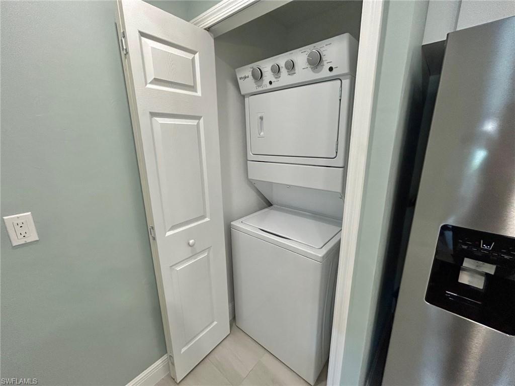 Laundry area featuring stacked washer / drying machine and baseboards