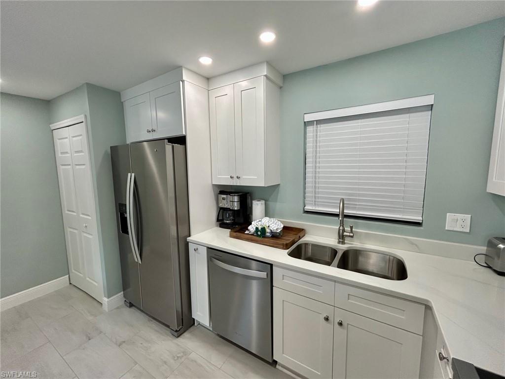 Kitchen featuring stainless steel appliances, white cabinets, light counters, recessed lighting, and light finish flooring