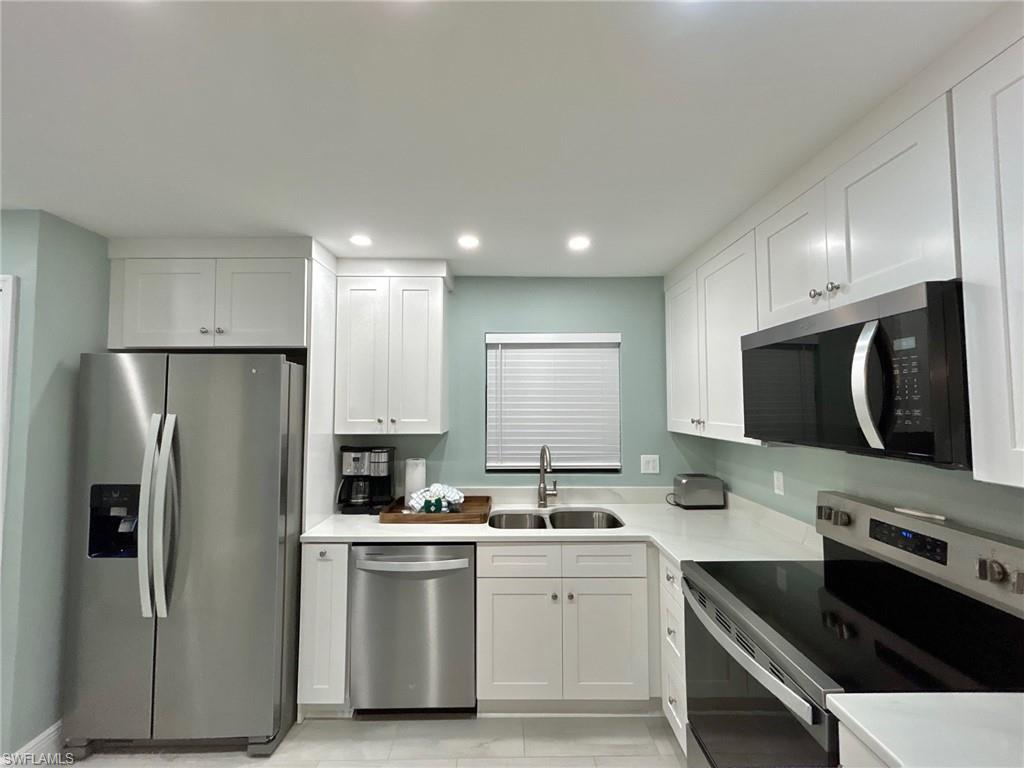 Kitchen with stainless steel appliances, white cabinetry, recessed lighting, and light countertops