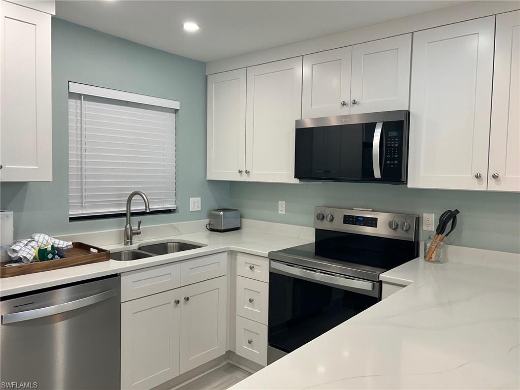 Kitchen featuring stainless steel appliances, white cabinets, light countertops, and recessed lighting