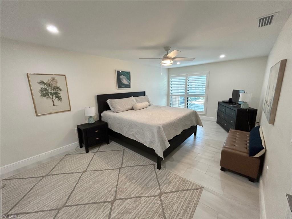 Primary bedroom with ceiling fan, recessed lighting, and light floors