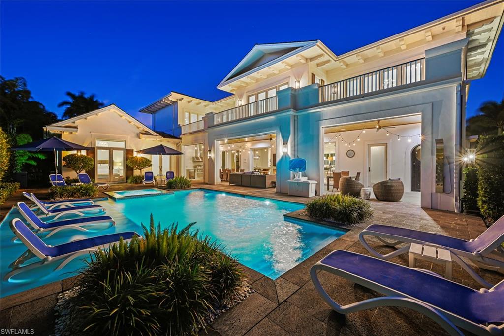 Back of house at night with a balcony, french doors, an outdoor lounge area, a patio area, and stucco siding