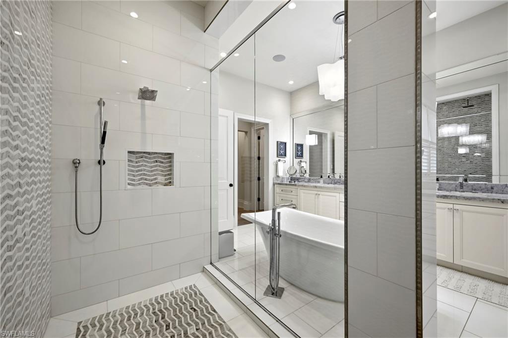 Bathroom with two vanities, walk in shower, a soaking tub, light tile patterned floors, and recessed lighting