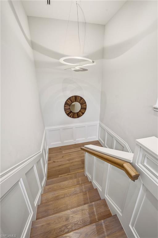 Stairway featuring a decorative wall, a wainscoted wall, and wood finished floors