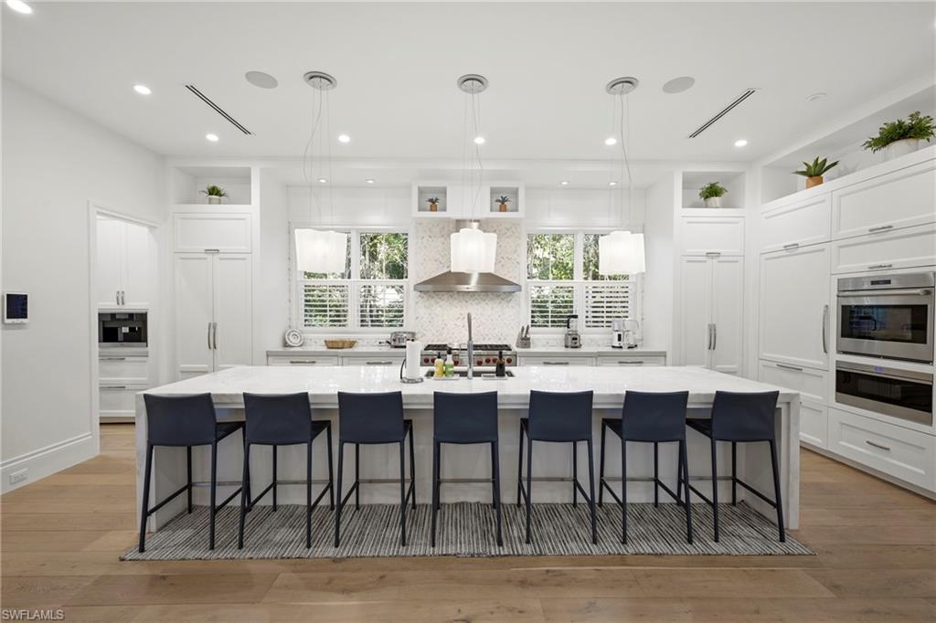 Kitchen with a breakfast bar area, light wood-style floors, a spacious island, and white cabinetry