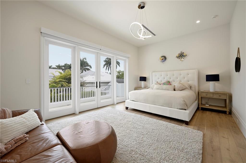 Bedroom with light wood-type flooring, access to outside, french doors, and hanging lights