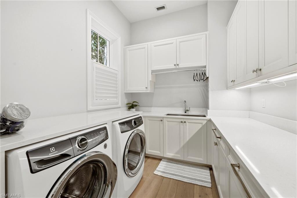 Laundry area featuring cabinet space, light wood finished floors, and washer and clothes dryer