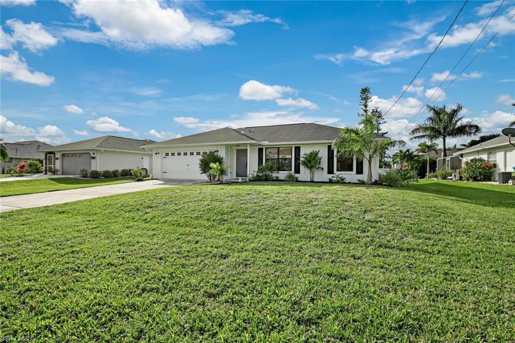 Ranch-style house featuring concrete driveway, a front yard, an attached garage, and stucco siding