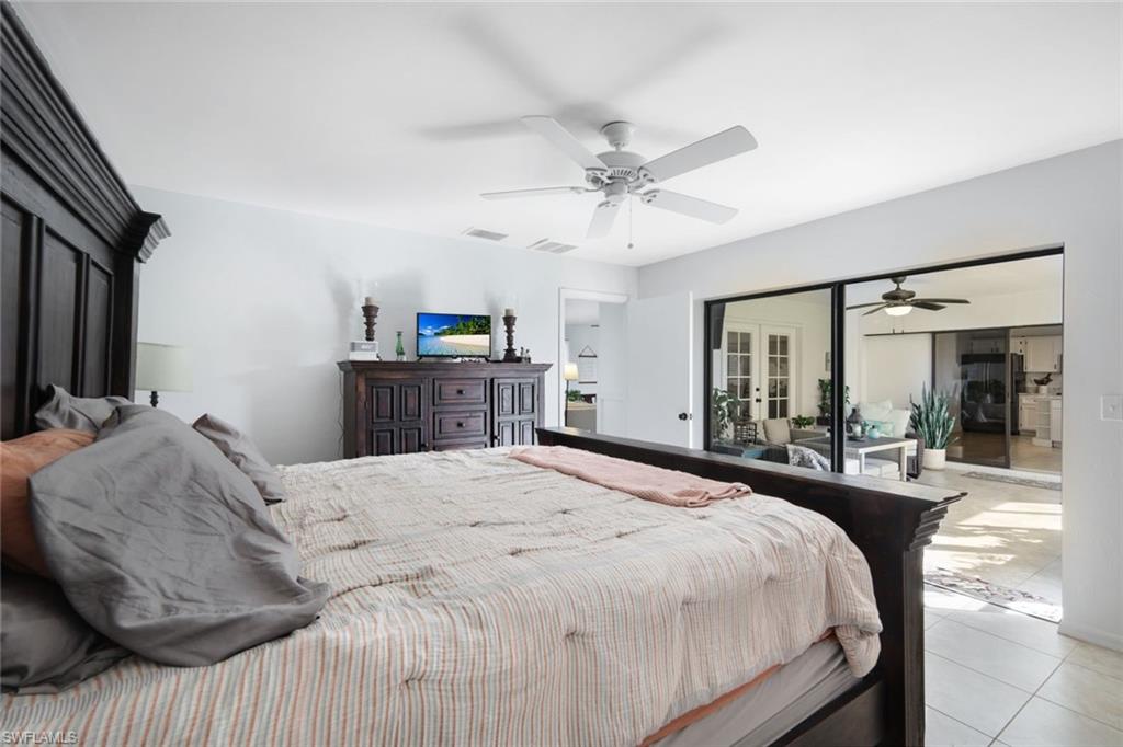 Tiled bedroom featuring access to exterior, freestanding refrigerator, and a ceiling fan