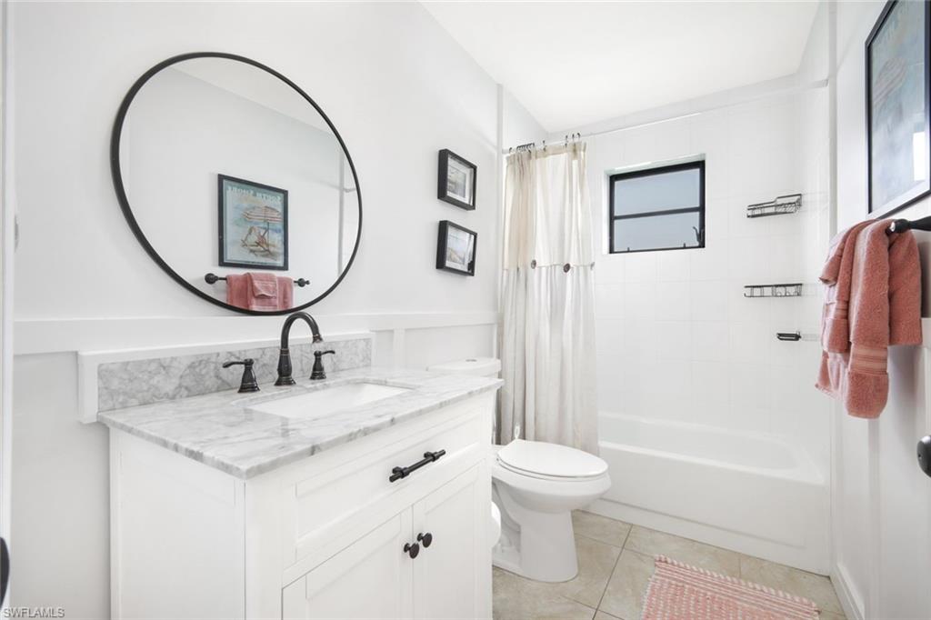 Full bath featuring vanity, shower / bath combo, and light tile patterned flooring