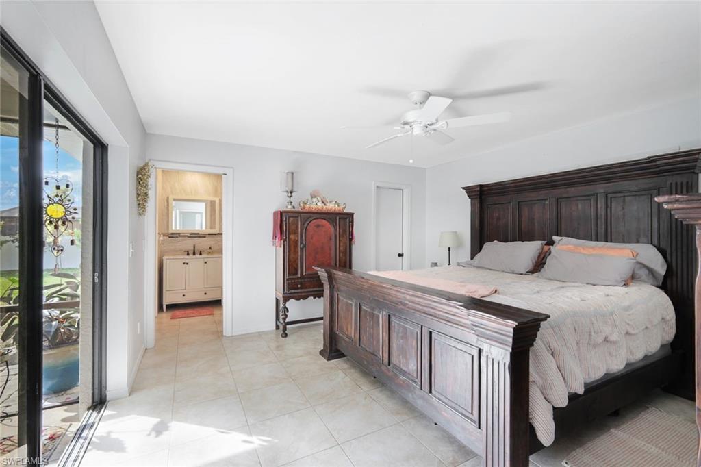 Bedroom featuring a ceiling fan, light tile patterned floors, and ensuite bathroom