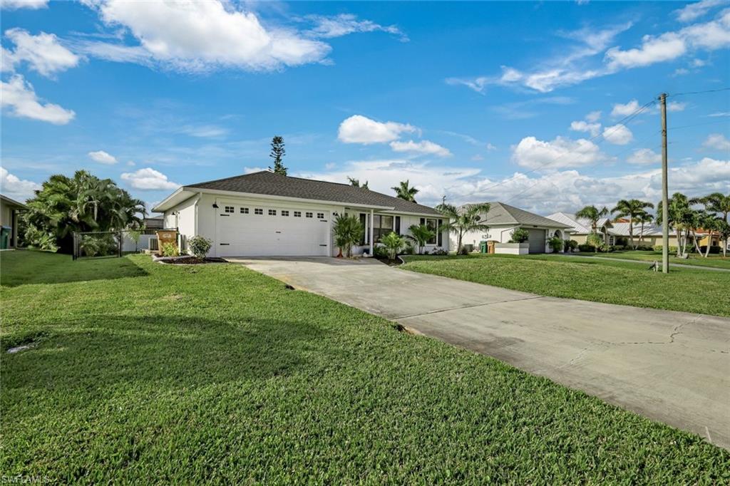 Single story home with a front lawn, a garage, concrete driveway, and stucco siding