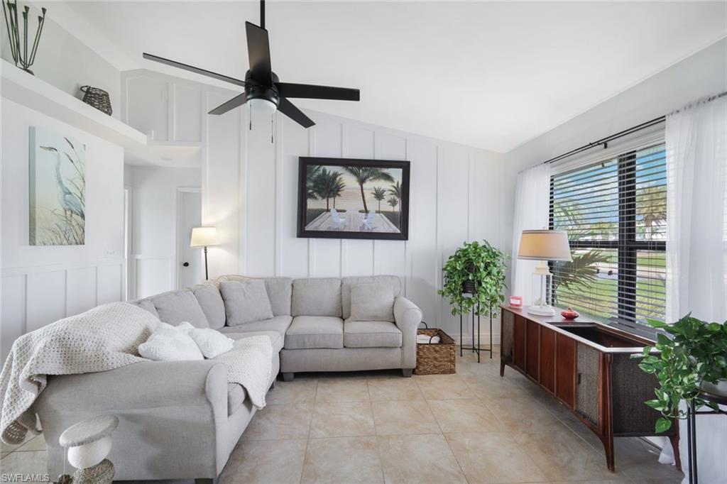 Living area featuring a decorative wall, lofted ceiling, and a ceiling fan