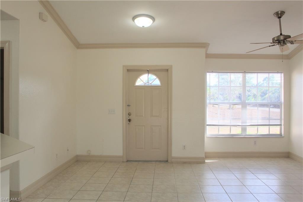 Entryway with ornamental molding, a ceiling fan, and light tile patterned flooring