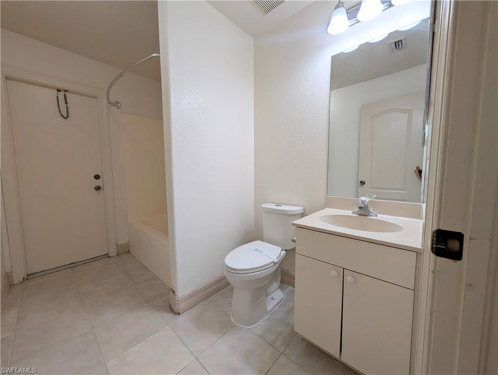 Bathroom with vanity, washtub / shower combination, and light tile patterned flooring
