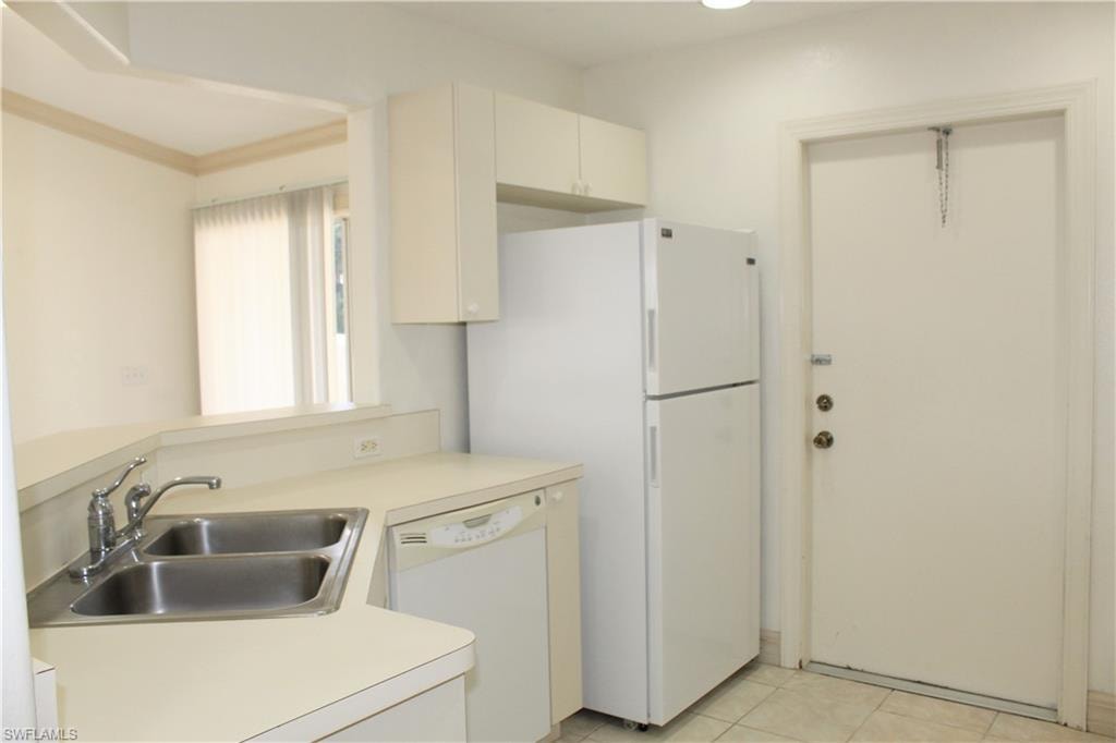 Kitchen featuring white appliances, light countertops, light tile patterned floors, a peninsula, and cream cabinets