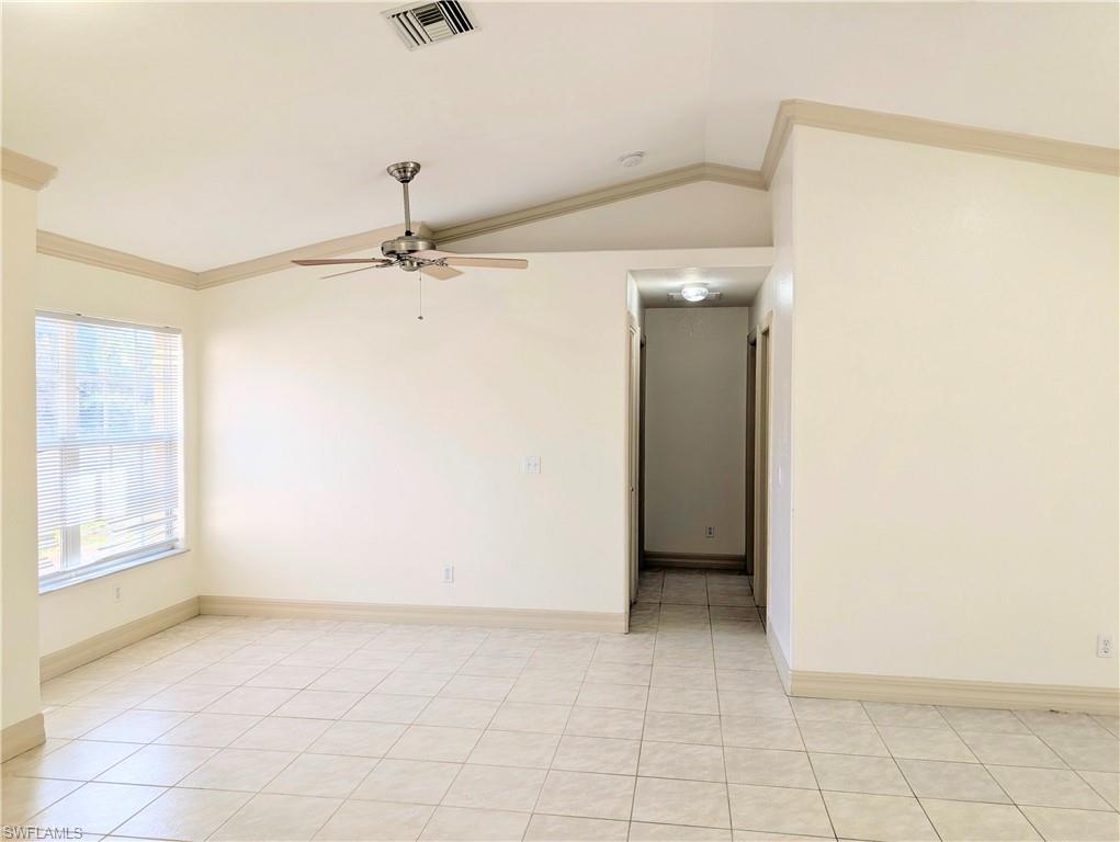 Unfurnished room featuring crown molding, ceiling fan, lofted ceiling, and light tile patterned floors