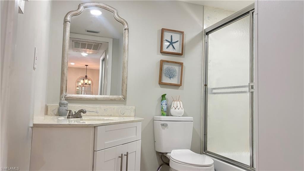 Bathroom with a stall shower, vanity, and suspended lighting