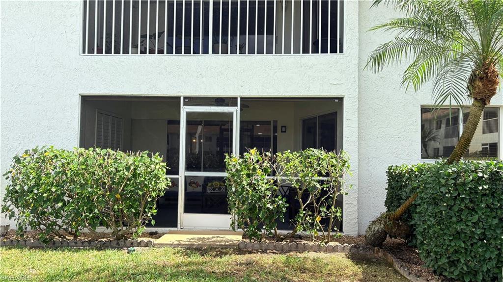 Doorway to property featuring stucco siding and a sunroom
