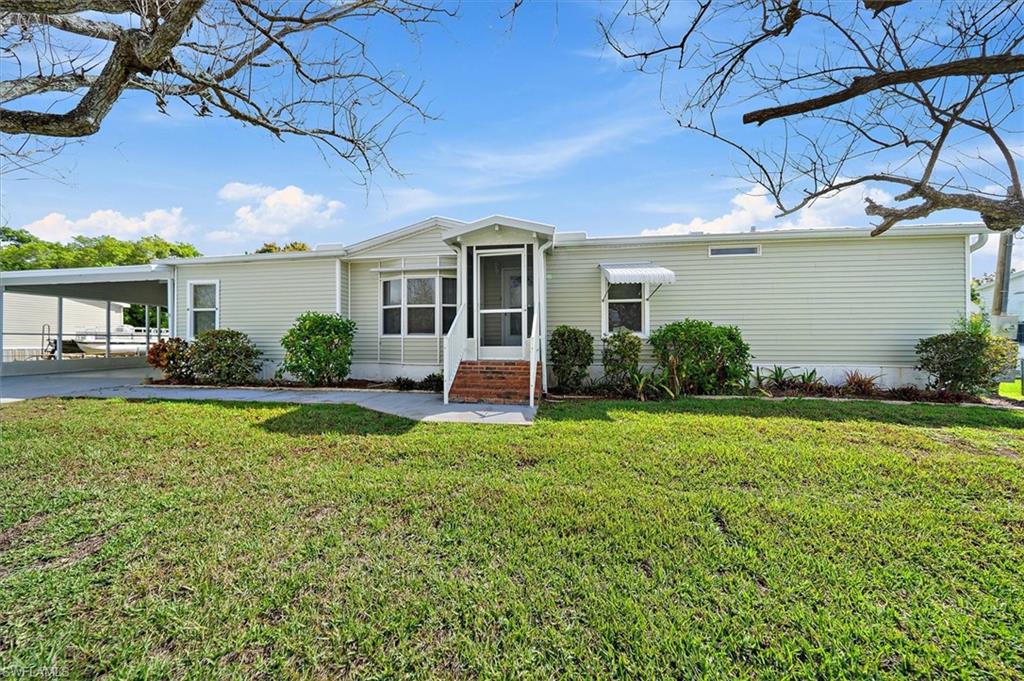 Manufactured / mobile home with an attached carport, a front yard, and entry steps