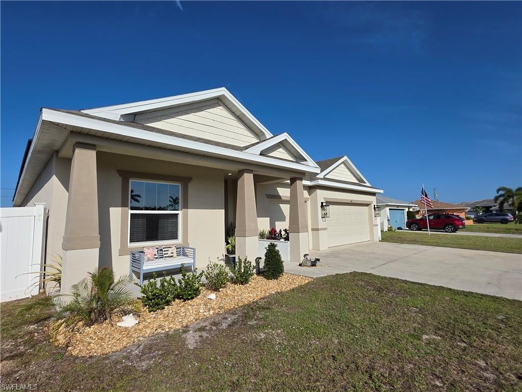 View of front of property featuring stucco siding, a porch, a garage, concrete driveway, and a front yard
