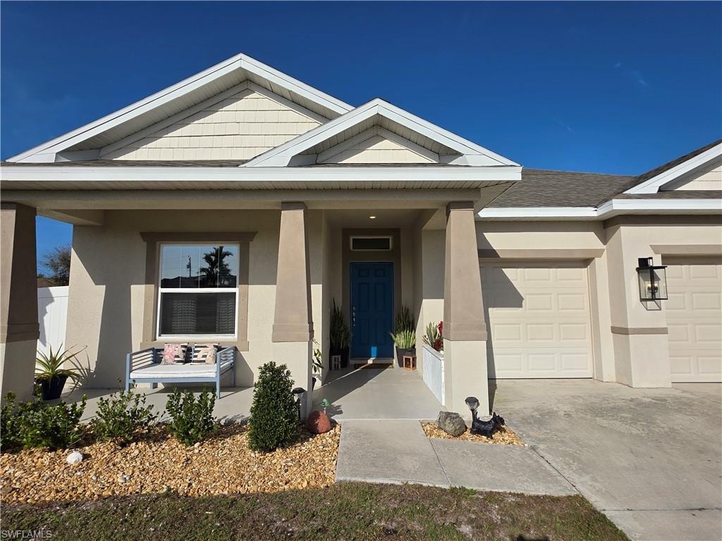 View of front of house featuring stucco siding, an attached garage, a porch, and driveway