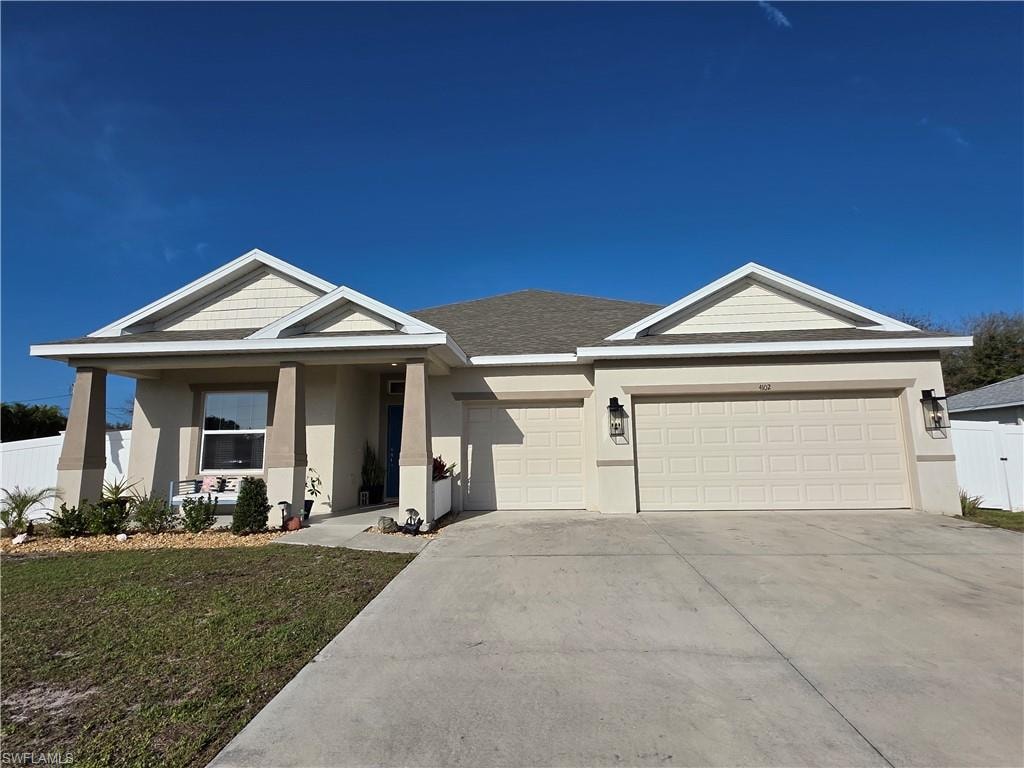 View of front of property with stucco siding, an attached garage, driveway, roof with shingles, and covered porch