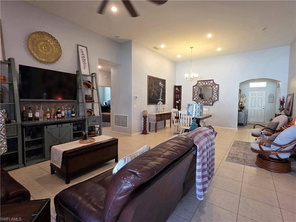 Living room featuring arched walkways, suspended lighting, a ceiling fan, and light tile patterned flooring