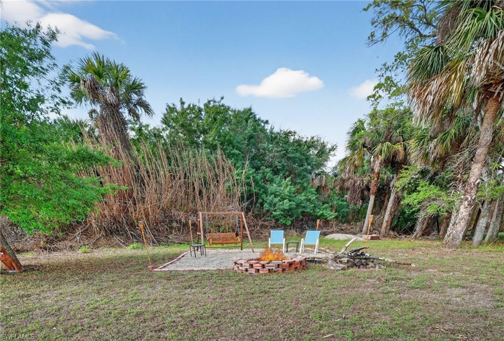 View of grassy yard with an outdoor fire pit and a patio
