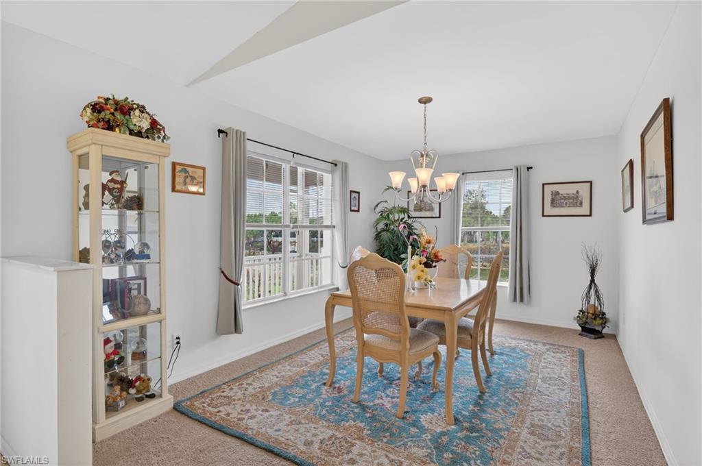 Carpeted dining room with baseboards and a chandelier