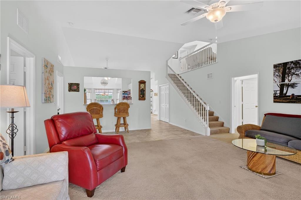 Living area featuring ceiling fan, light carpet, and lofted ceiling