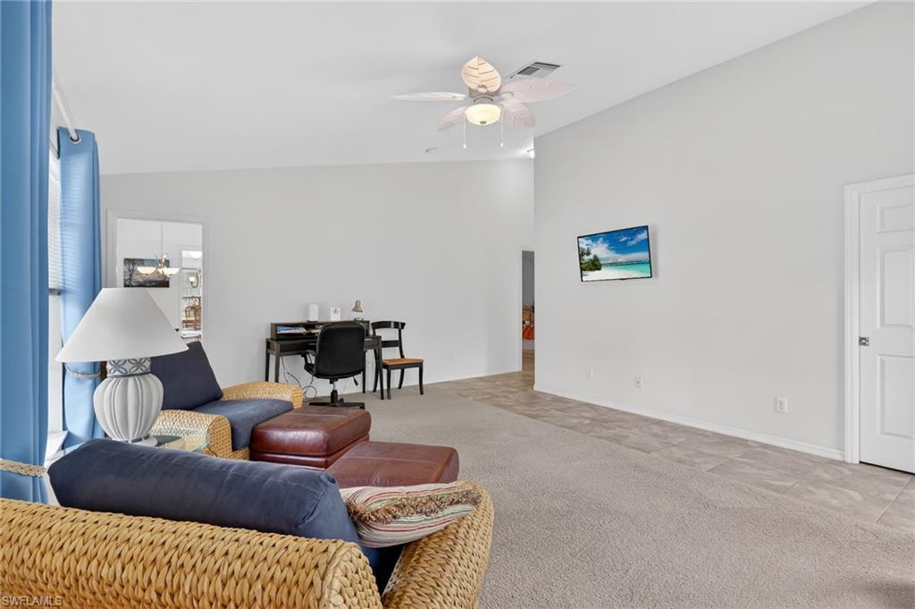 Carpeted living room featuring lofted ceiling, an office area, and ceiling fan