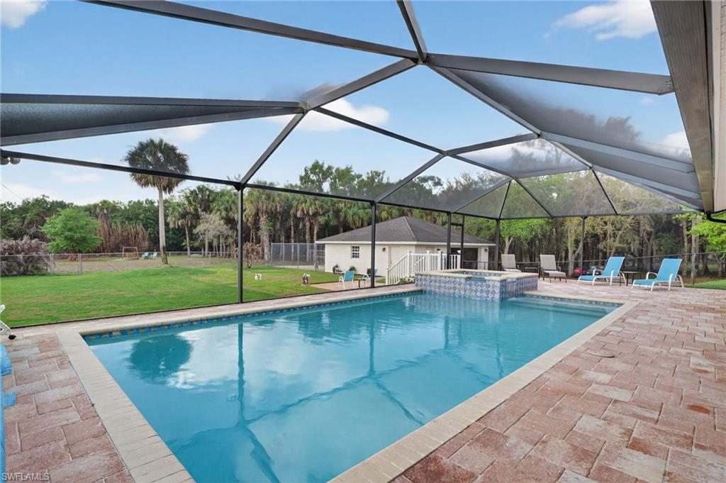 Combined pool / hot tub featuring glass enclosure, a patio area, and a sunroom