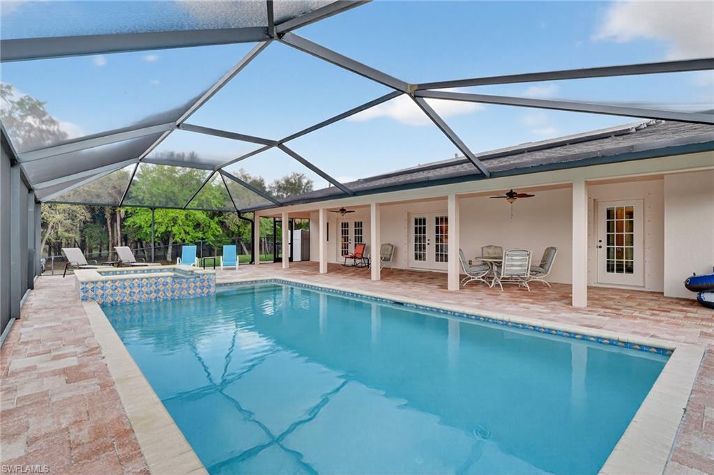 Integrated pool / hot tub with french doors, glass enclosure, a sunroom, and a patio