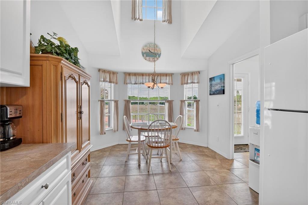 Dining area with plenty of natural light, hanging lights, light tile patterned flooring, and a high ceiling