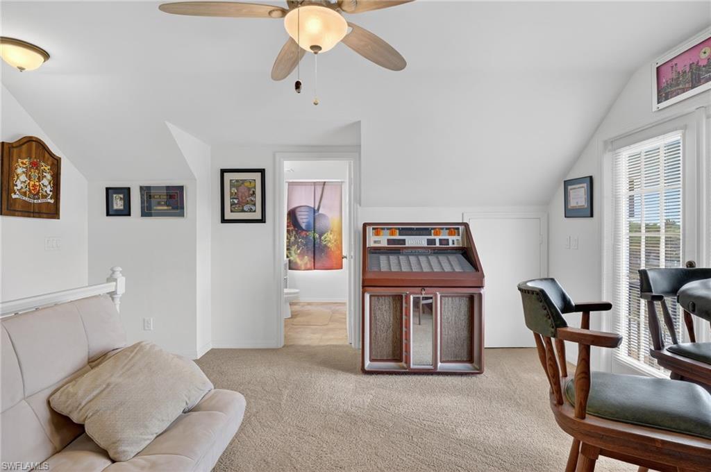 Living area featuring lofted ceiling, carpet flooring, and ceiling fan