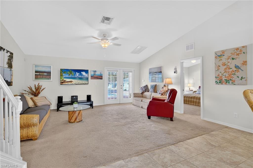 Living area featuring light colored carpet, lofted ceiling, a ceiling fan, and french doors