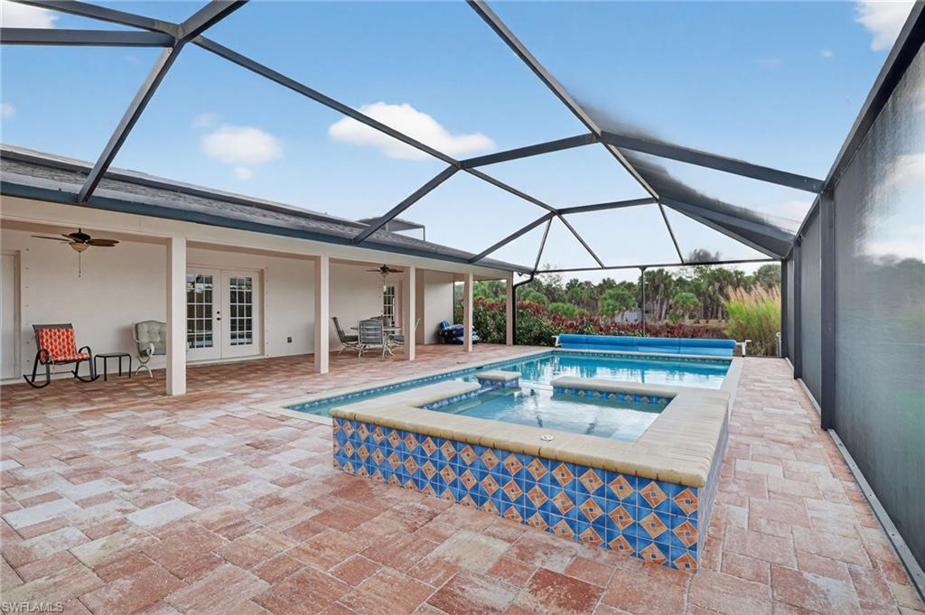 Integrated pool / spa featuring a sunroom, a patio, french doors, and glass enclosure