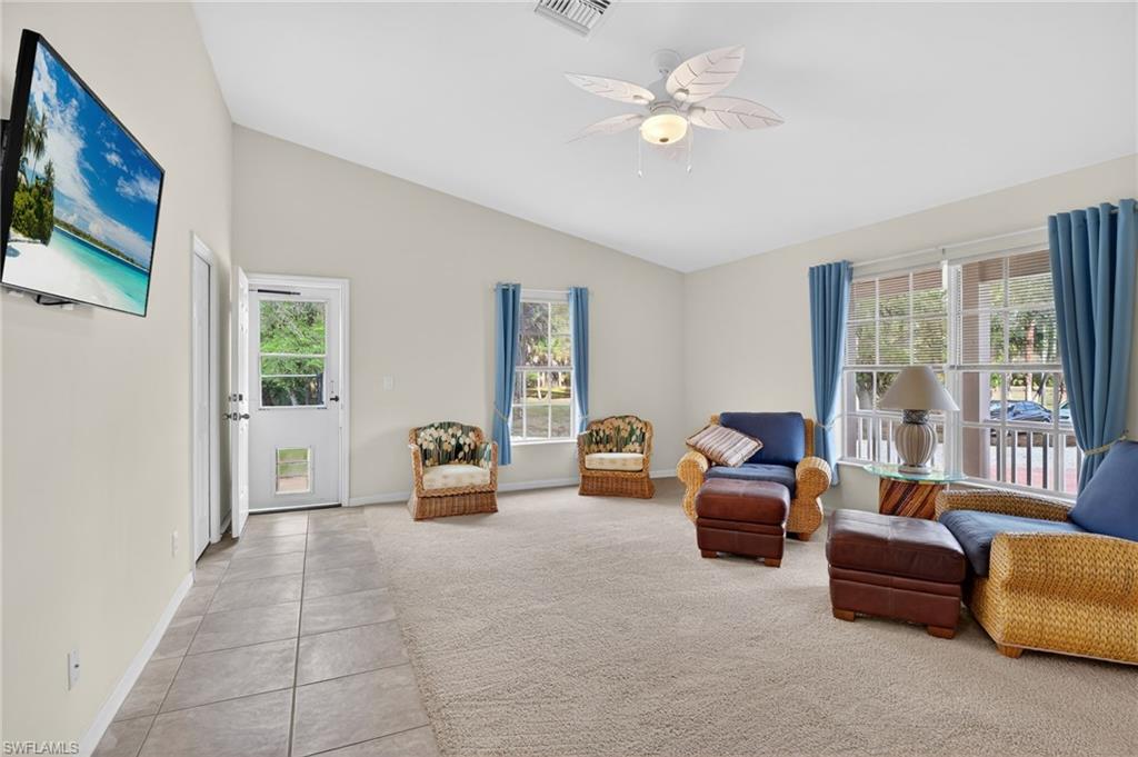Sitting room featuring a ceiling fan, light colored carpet, light tile patterned floors, and lofted ceiling