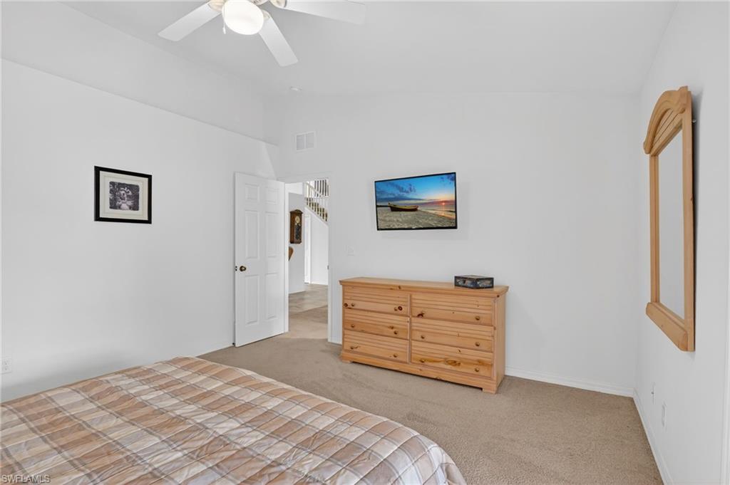Carpeted bedroom featuring lofted ceiling and a ceiling fan
