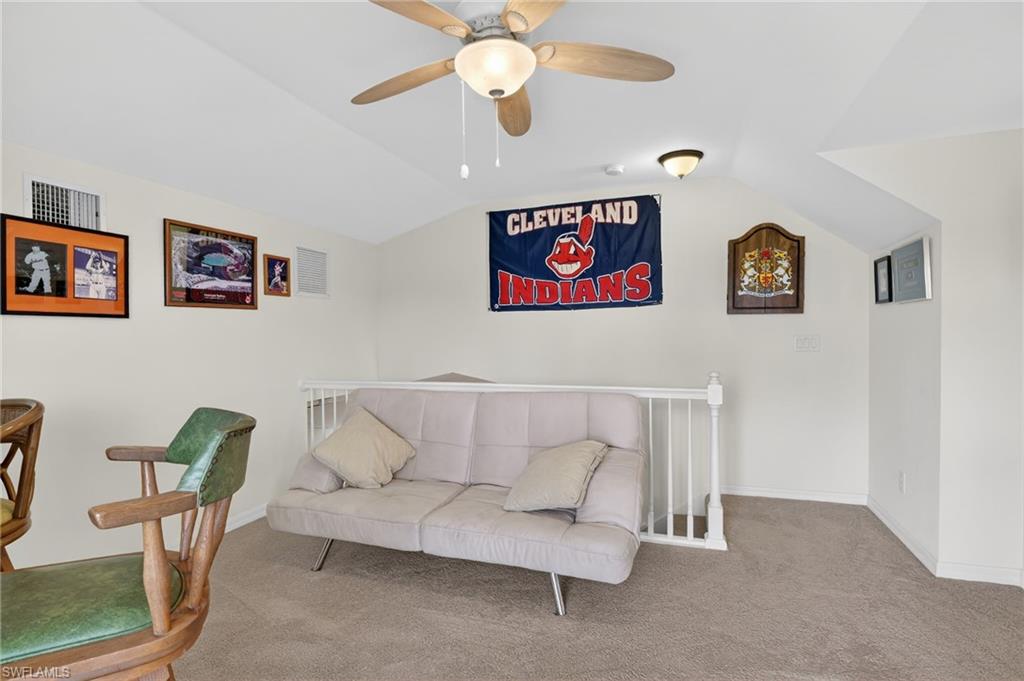 Living area with lofted ceiling, a ceiling fan, and carpet floors