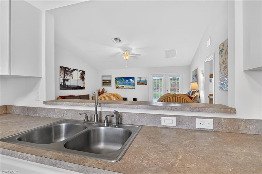 Kitchen with ceiling fan, open floor plan, light countertops, french doors, and white cabinetry