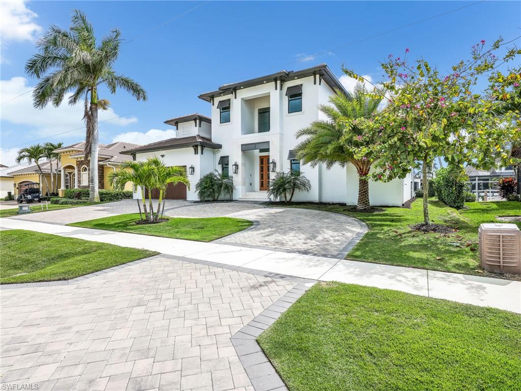 View of front facade featuring curved driveway, stucco siding, and a front lawn