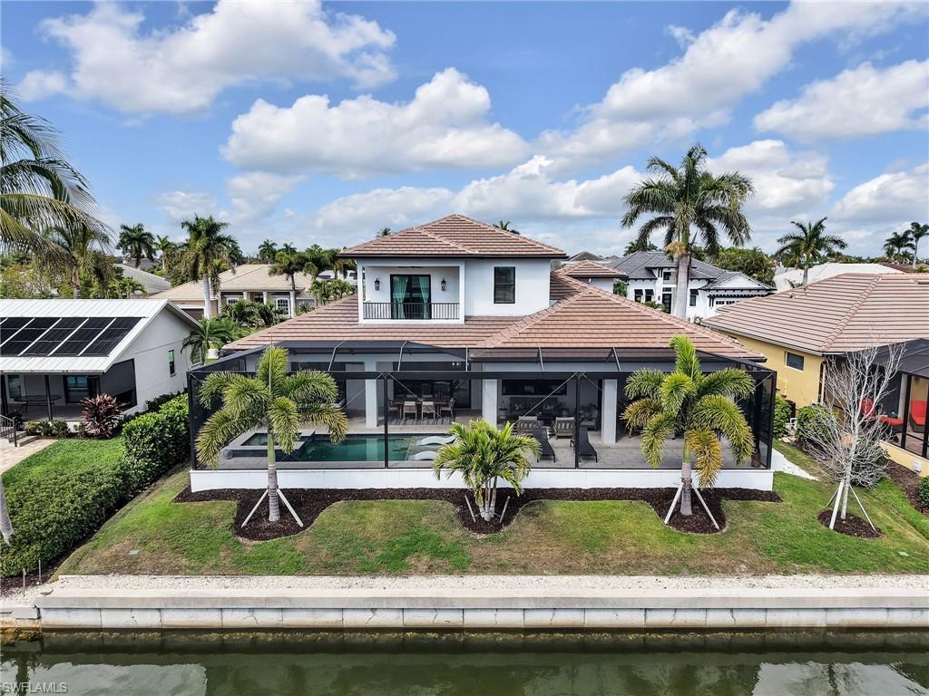 Rear view of property with an outdoor pool, a lanai, a tile roof, and a lawn