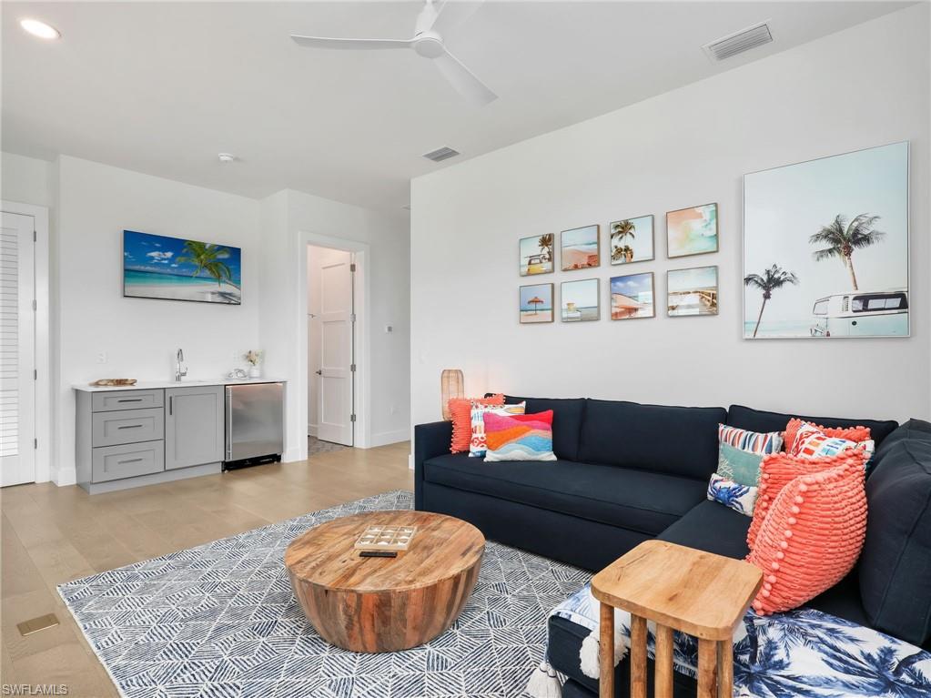 Living area featuring ceiling fan, wet bar, and light wood-style floors